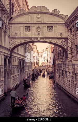 Venice, Italy - May 18, 2017: Gondolas with tourists are sailing along the narrow canal under famous Bridge of Sighs at the Doge`s Palace. The gondola Stock Photo